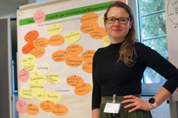 Olga Wagner vor dem Plakat "Vision einer Zukunft der Hochschule/Wissenschaft"
