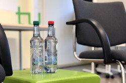 2 Wasserflaschen auf grüner Box mit weißem TU Logo