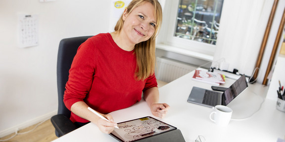 Nadine Roßa sitzend am Schreibtisch